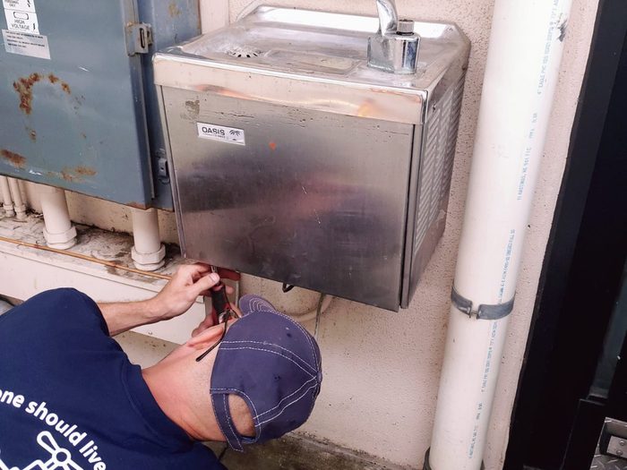 Durbin Plumbing technician working under a commercial drinking fountain